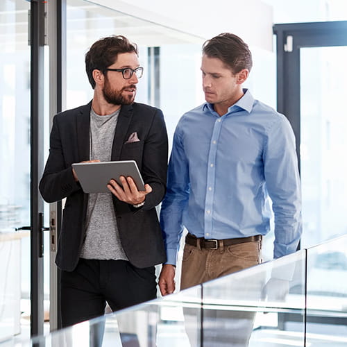 two businessmen walking and talking about information on iPad