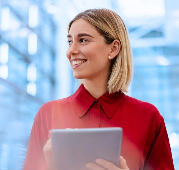 Ung blond kvinna i röd blus med surfplatta i handen