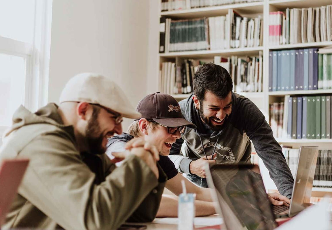 IT-team som skrattar tillsammans framför skärmen