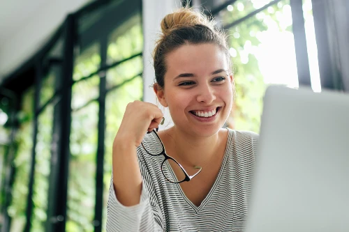 Ung kvinna framför laptop - jobbar hemifrån som konsult